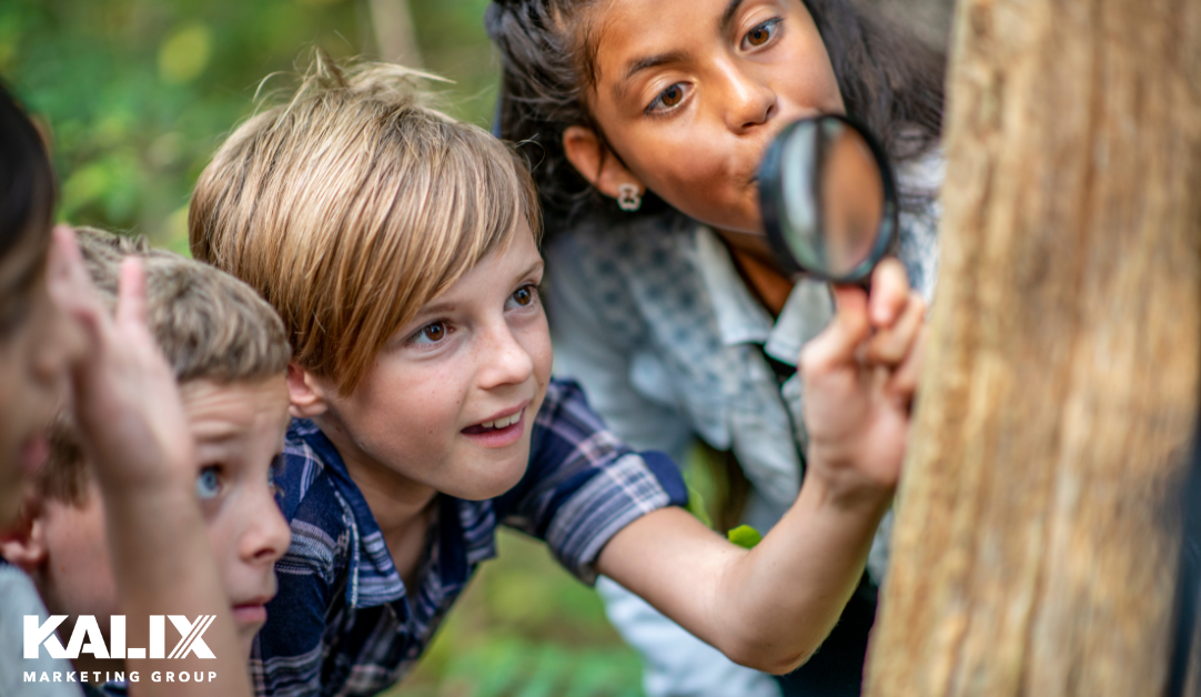 Children looking at a tree through a magnifying glass